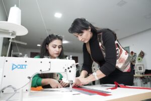 Two women collaborate on a sewing project in a modern workshop, focusing on fabric design.