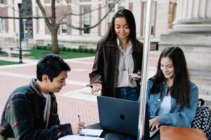 Group of university students collaborating and studying together in an outdoor setting.